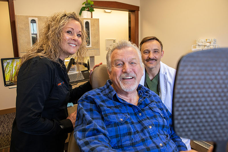dental implant patient smiling in mirror